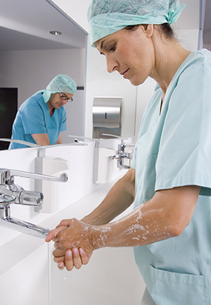 Healthcare provider washing hands in hospital room.
