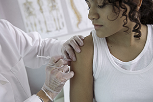 Healthcare provider giving teenage girl an injection.