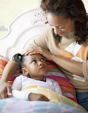 Mother comforting young daughter who is in bed