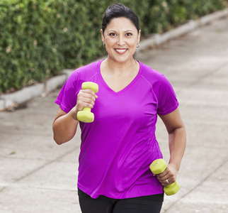 Woman jogging outdoors, carrying hand weights
