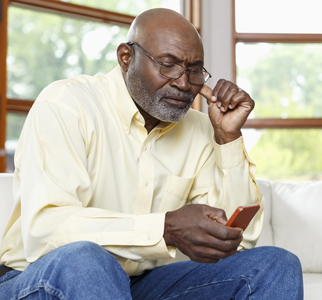 Older man, seated, looking at his cell phone