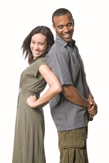 A woman and man smiling, standing back to back