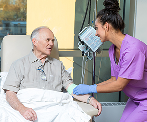 Healthcare provider caring for man having infusion treatment.