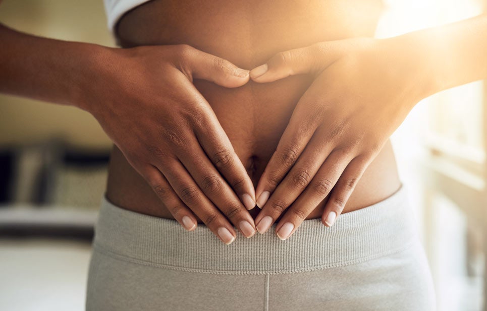 Closeup of woman holding hand over stomach